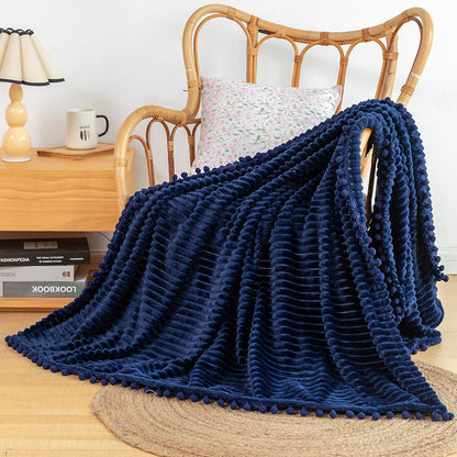 Pom fringe blanket with striped velvet texture used as decorative bed throw
