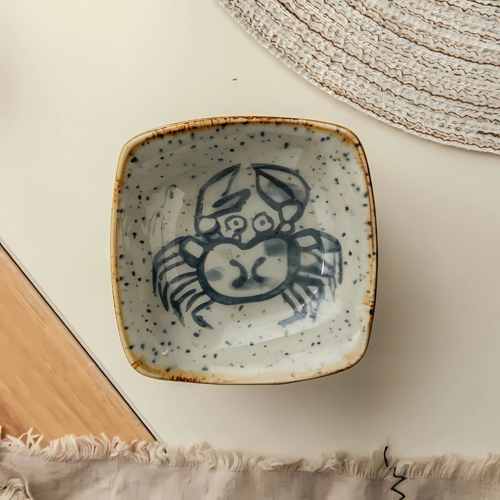 Speckled ceramic glaze with intricate sea life motifs creating unique coastal dining aesthetic