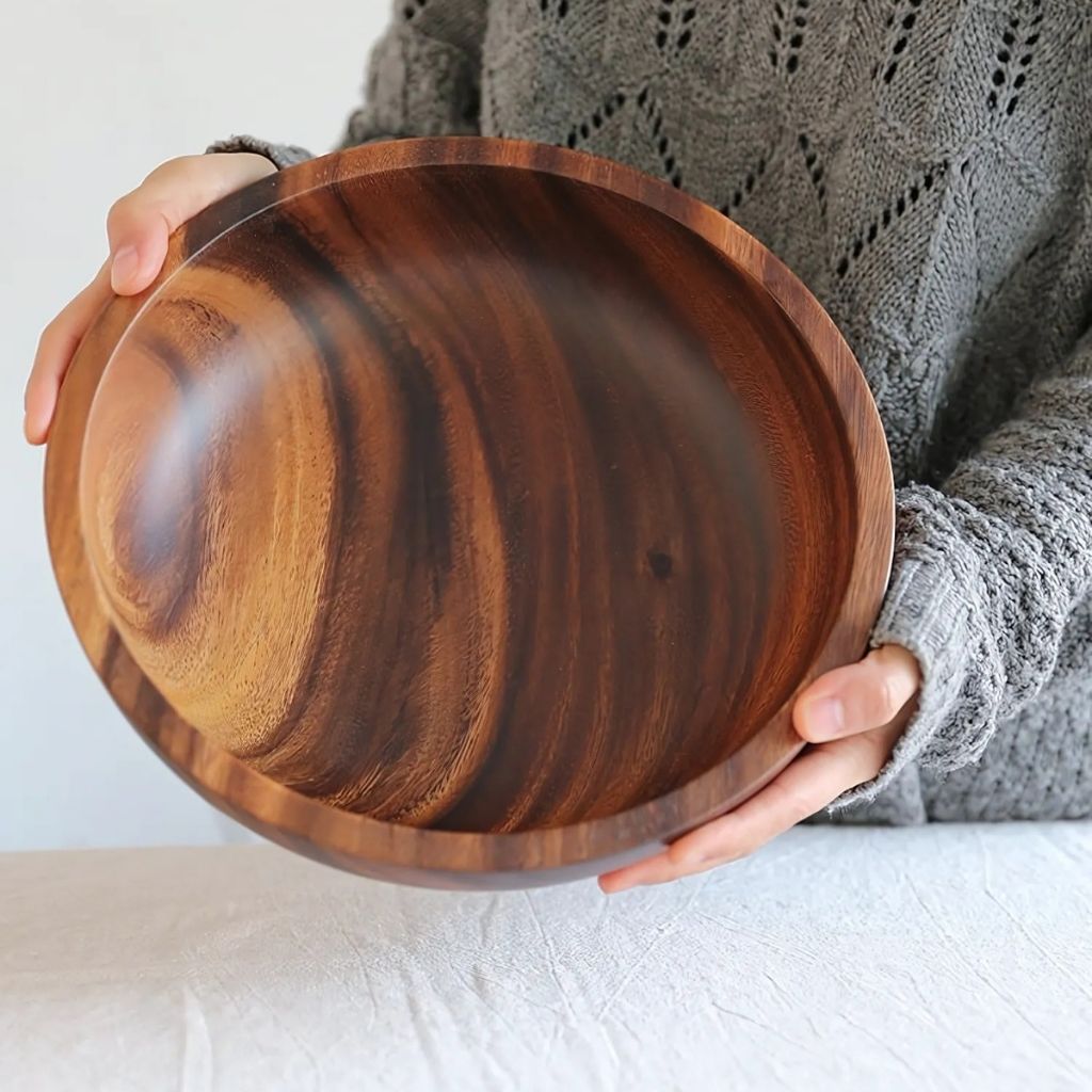 Person holding a wooden bowl with a plain background