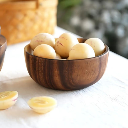 Wooden bowl filled with peeled potatoes on a light surface