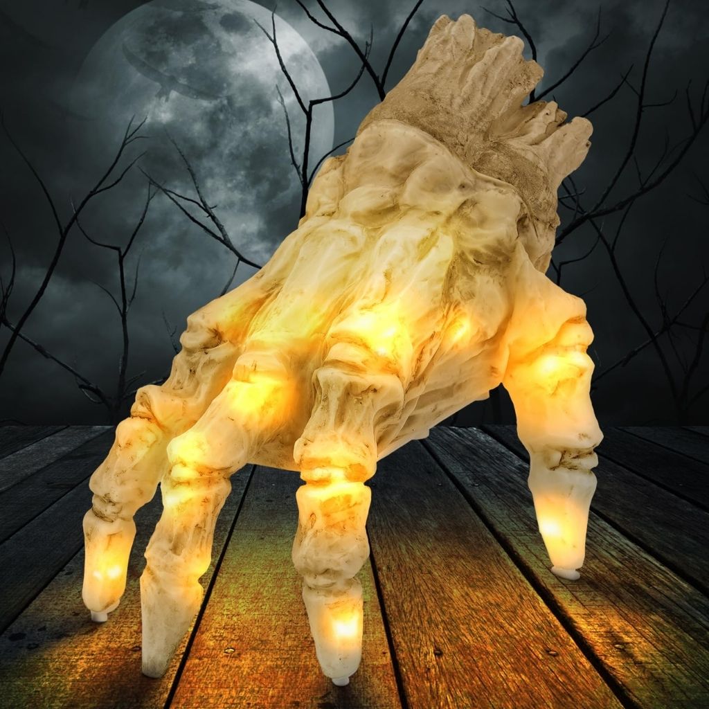 Light-up skeleton hand on a wooden surface with a dark, moonlit background