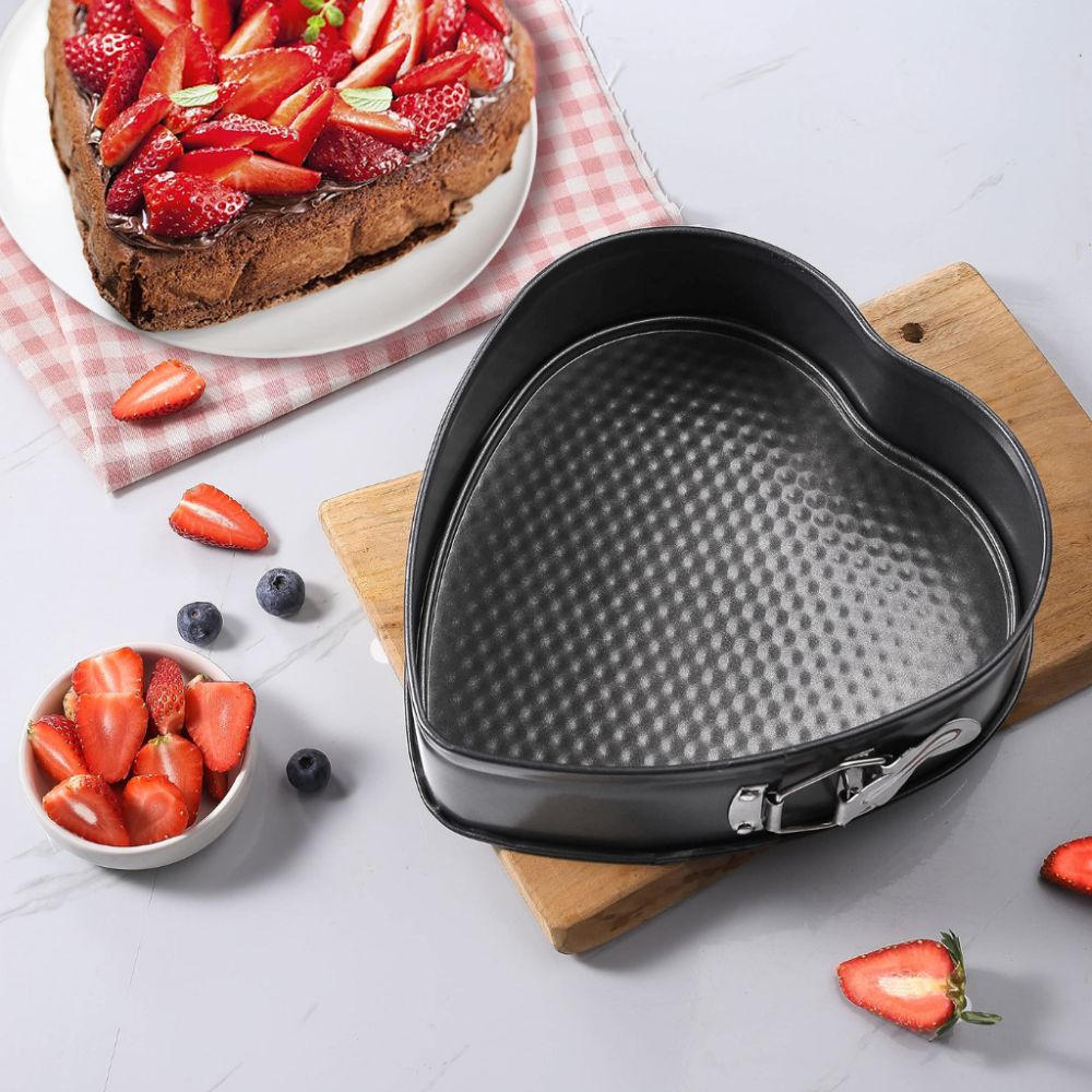Heart-shaped cake pan on a wooden board with strawberries and blueberries around