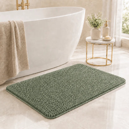Green bath mat in front of a white bathtub with a towel and small table in a bathroom.