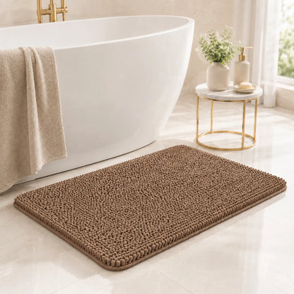 Brown bath mat in front of a white freestanding bathtub with a towel and small table in a bathroom.