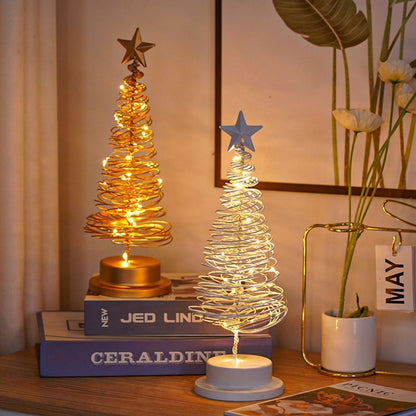 Two decorative LED tree lights on books with a vase and plant in the background.