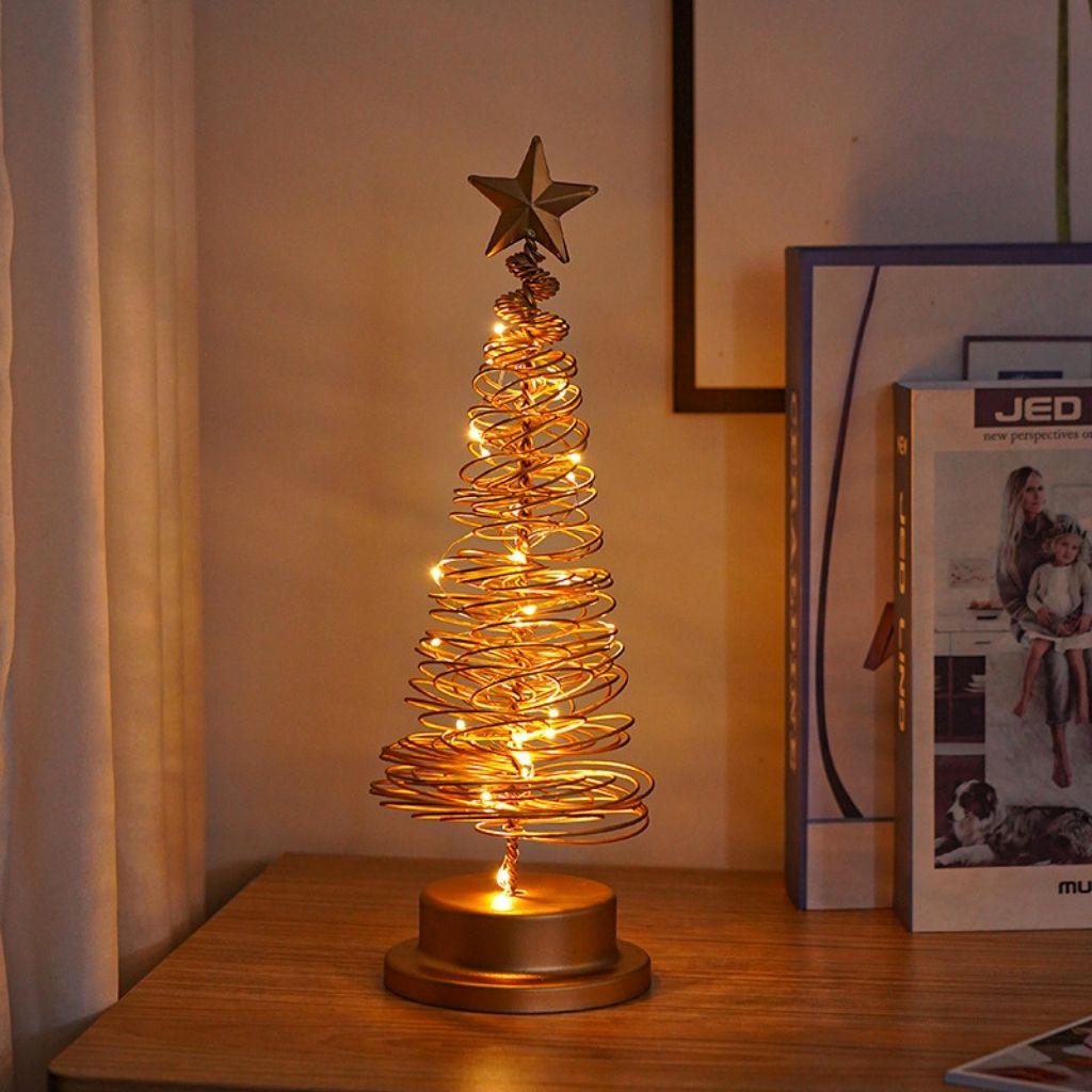 Decorative table lamp shaped like a Christmas tree with lights on a wooden surface.