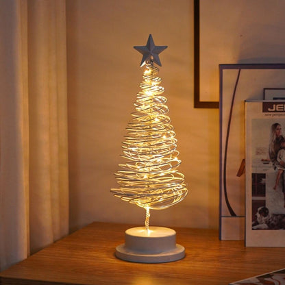 Decorative LED Christmas tree lamp on a wooden surface with a star on top.