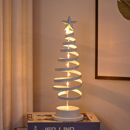 Decorative spiral Christmas tree lamp with a star on top, placed on a box against a neutral wall.