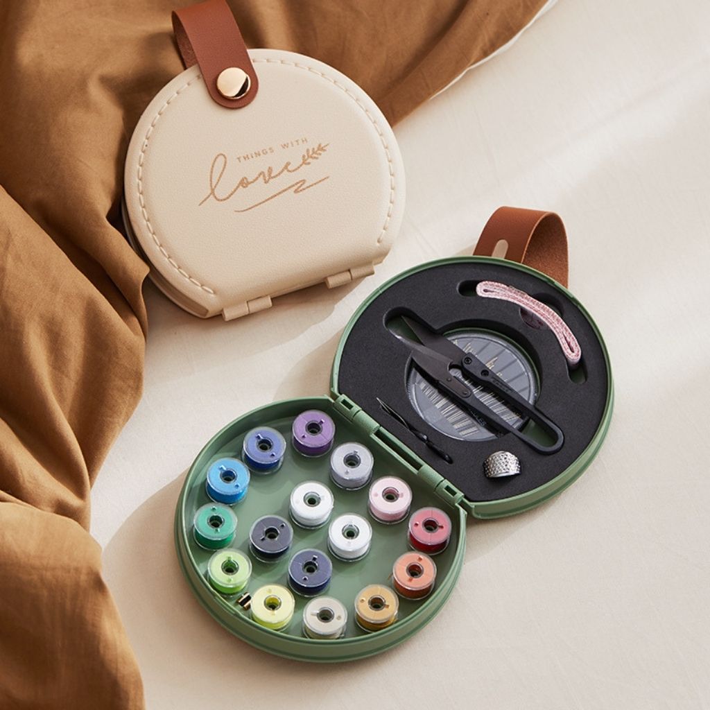 Compact travel sewing case featuring assorted thread spools, needles, scissors and measuring tape essentials