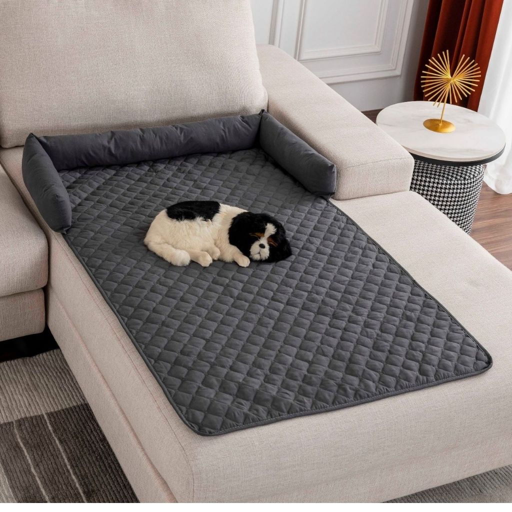 Waterproof quilted pet bed mat placed on gray upholstered sofa
