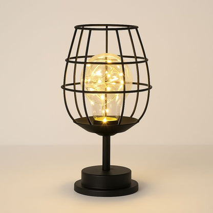 Black cage-style table lamp with a glowing light bulb on a beige background