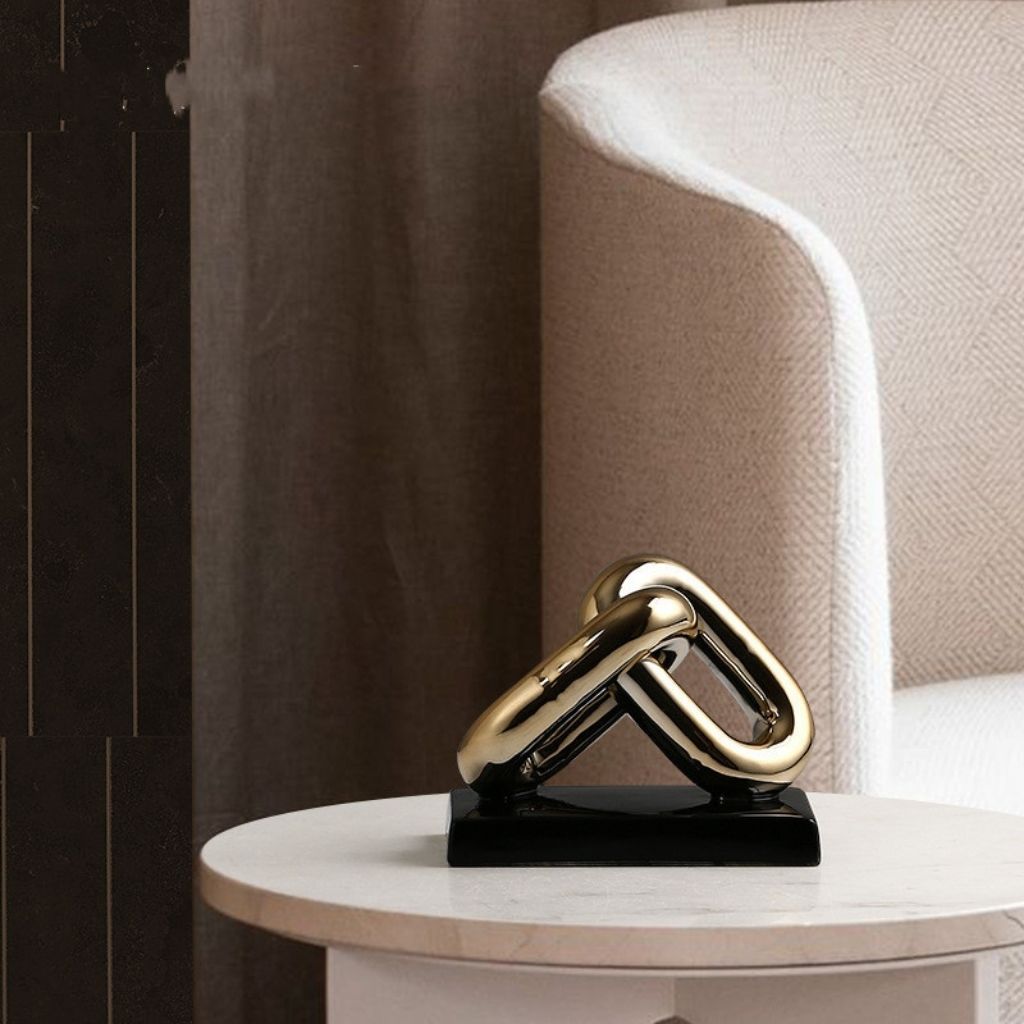 Gold metal sculpture on a black base on a round table with a neutral background