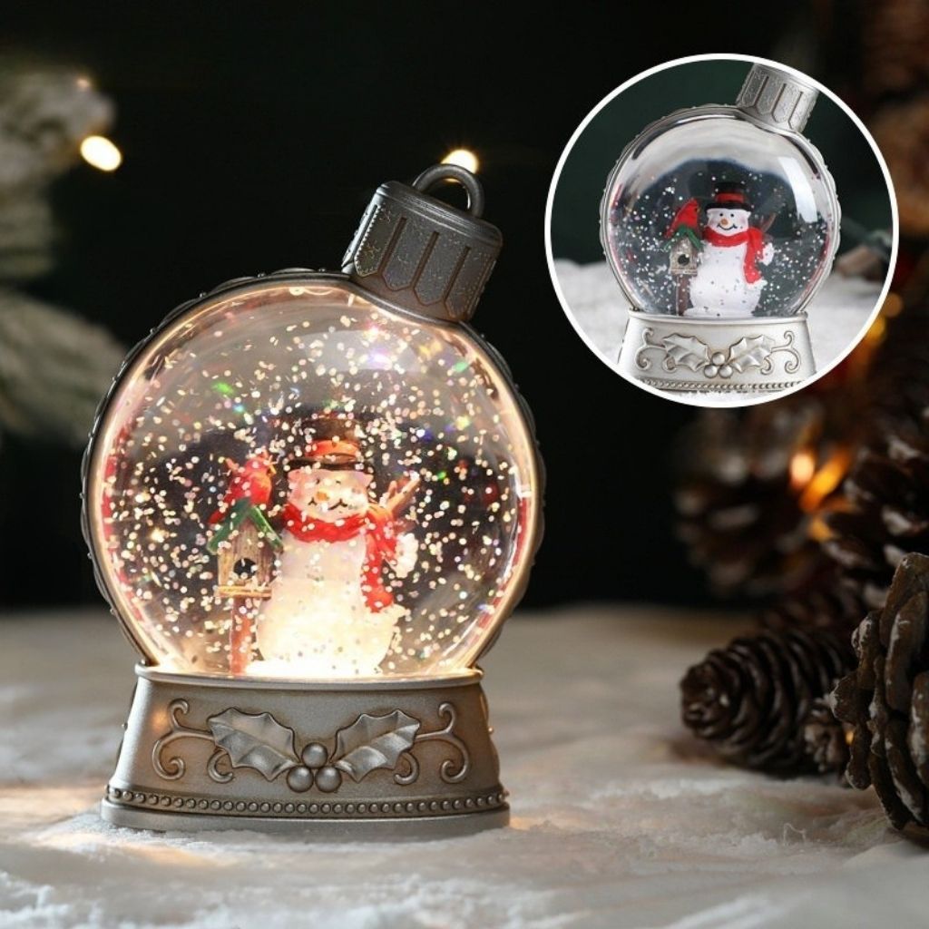 Glitter filled LED snow globe showing festive winter scene with warm glow