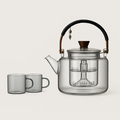 Clear glass tea set with teapot and cups on neutral background