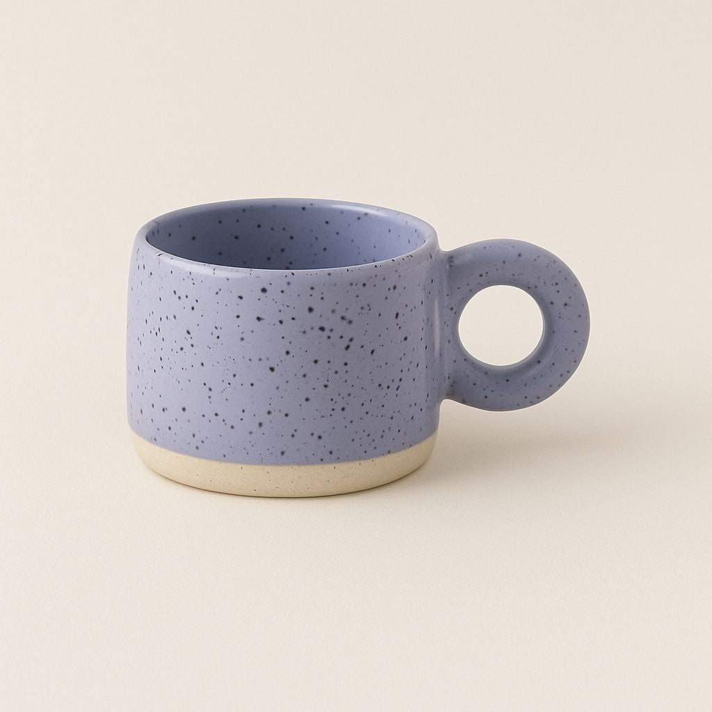 Ceramic coffee mug featuring distinctive circular handle and speckled texture for comfortable grip