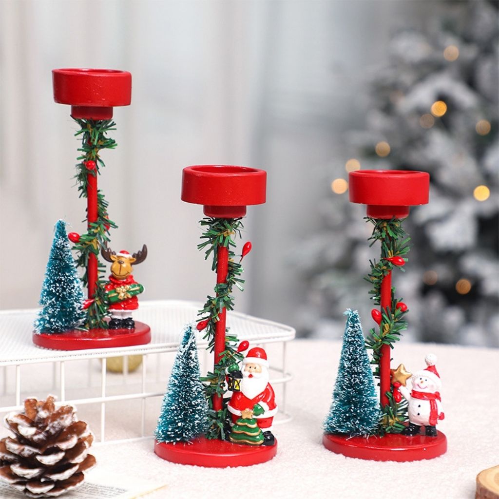 Resin candle stand with miniature Christmas scene and wrapped greenery on white base