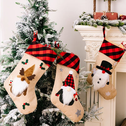 Three Christmas stockings with festive designs hanging on a tree.