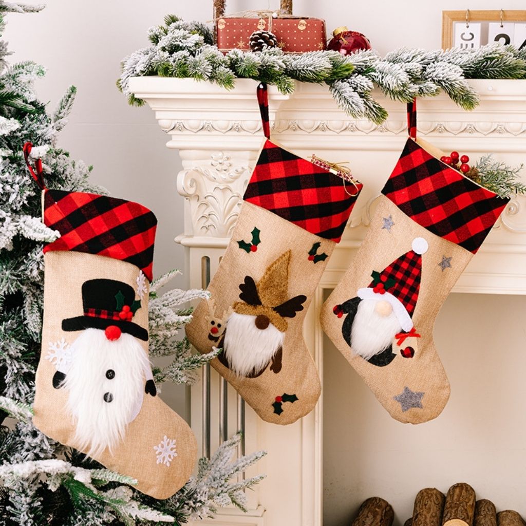 Three Christmas stockings with festive designs hanging on a fireplace mantle.