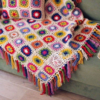Floral motif blanket with hand crocheted design and vibrant decorative tassel details