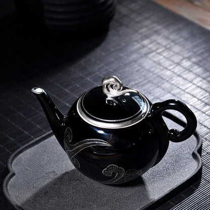 Handcrafted black glazed ceramic teapot with decorative silver detailing for tea ceremony
