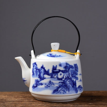 White kaolin teapot showing painted trees and mountains on smooth surface