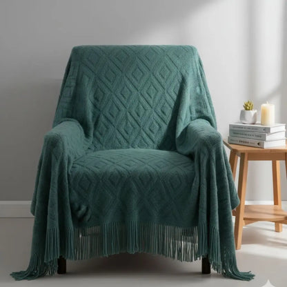 Fringed knit throw blanket draped over furniture showing jacquard weave pattern and fringe detail