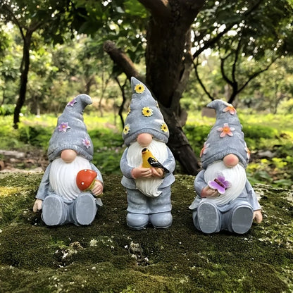 Three piece resin gnome set with red yellow and blue hats arranged on outdoor patio