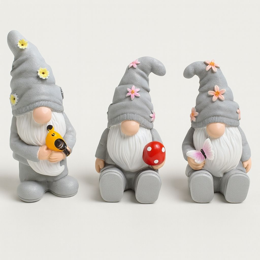 Three resin garden gnomes with colorful hats and beards displayed together on outdoor surface