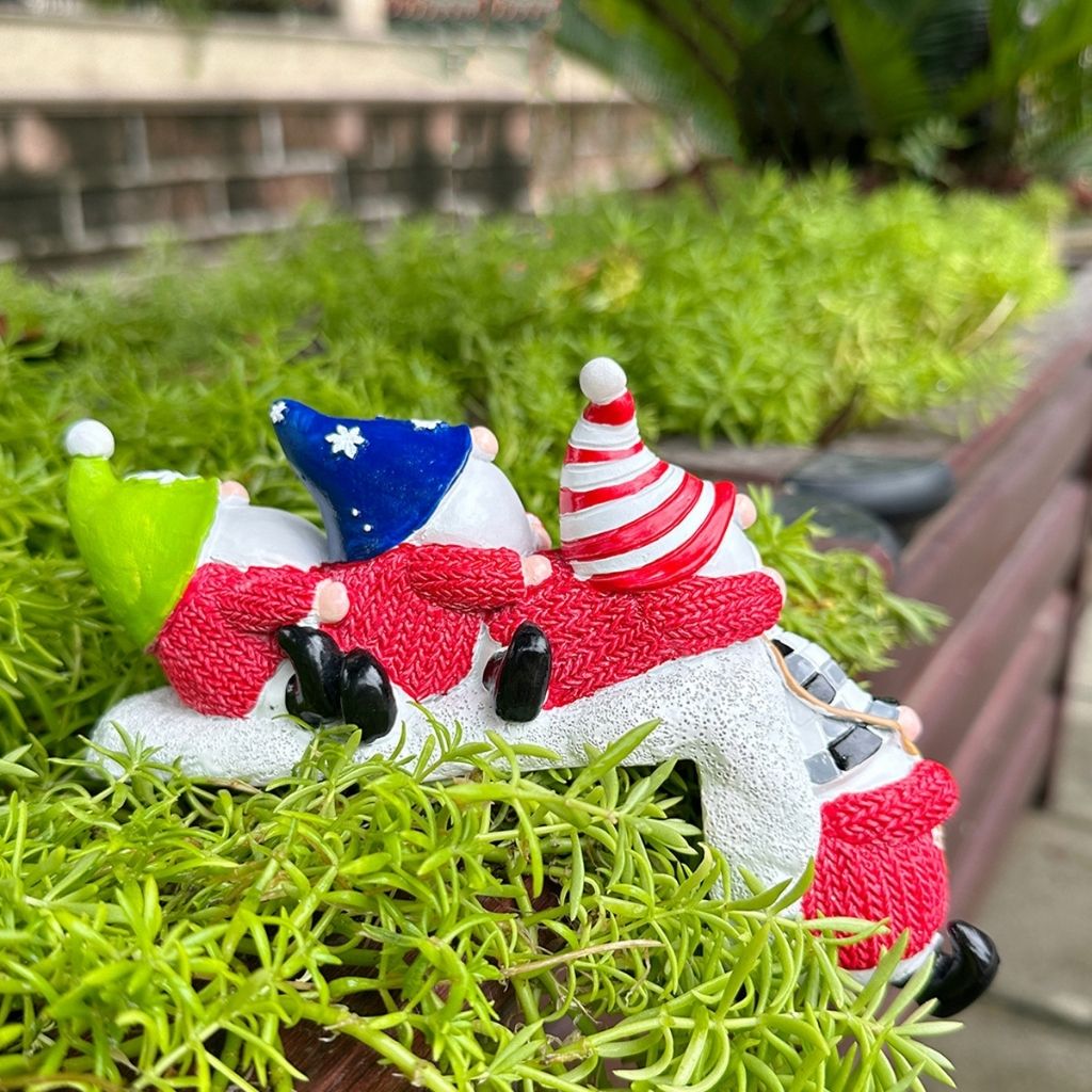 Textured resin figurine showing faceless Christmas characters with distinctive hats and sculptural carved details
